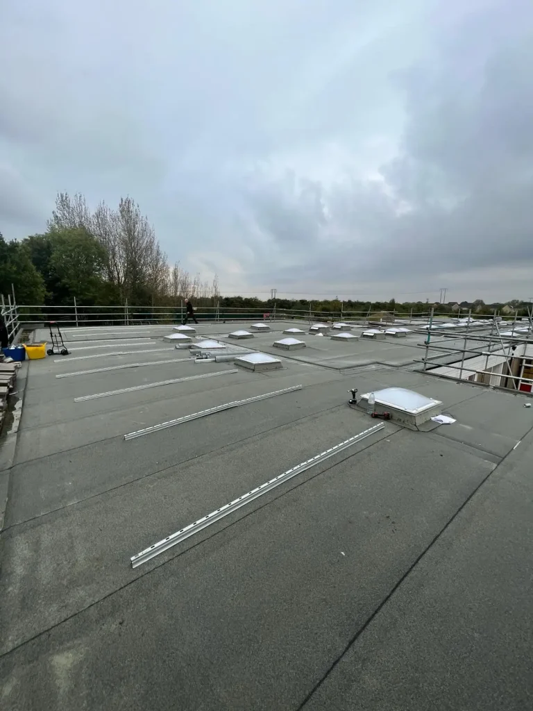 Flat rooftop with rectangular skylights and metal mounting rails installed across surface
