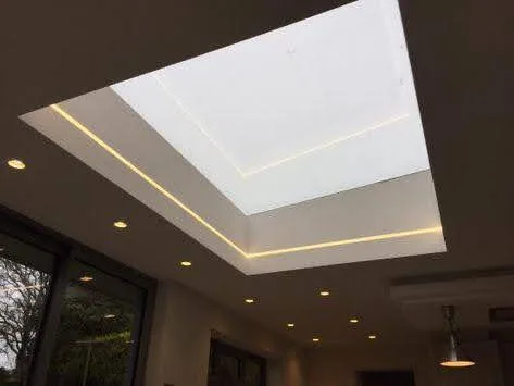 Modern interior with large rectangular skylight framed by recessed lighting, ceiling spotlights, and side windows