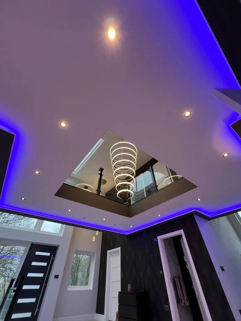 Modern interior with spiral chandelier, blue LED ceiling lights, recessed lighting, and high square cutout revealing upper level