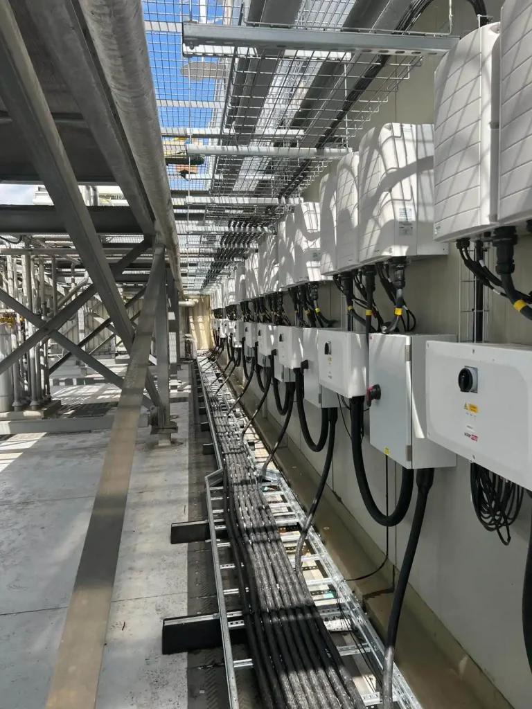 Industrial electrical installation with multiple white control boxes, organized cable trays, and metal supports