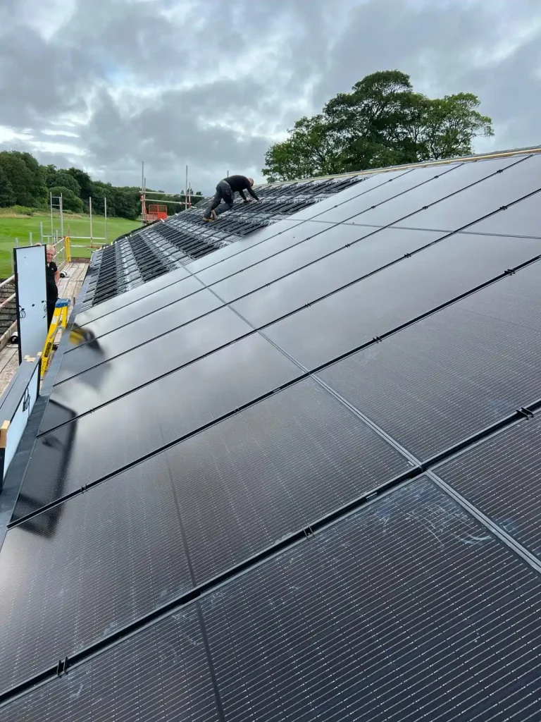 Technician installing solar panels on sloped roof with scaffolding and cloudy sky in background